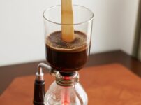 サイフォンガラスを竹ベラで攪拌している